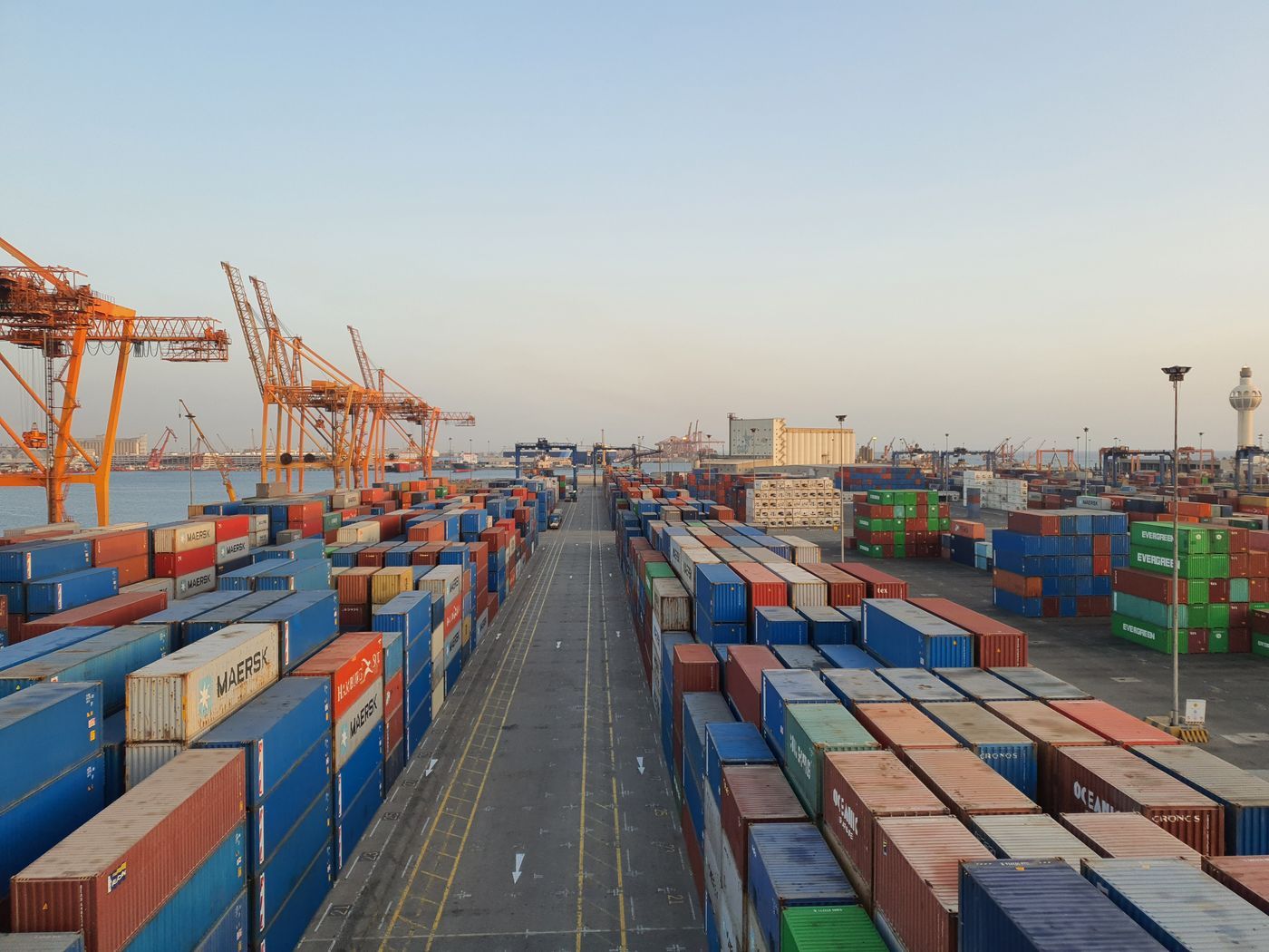 Shipping containers and cranes at a cargo port at sunrise