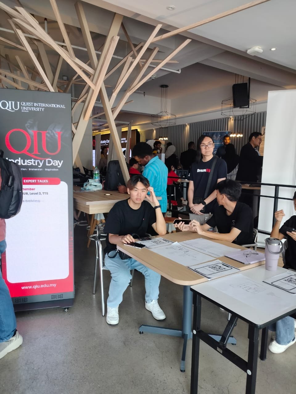 QIU Industry Day 2026 expert talks standee with students at the event