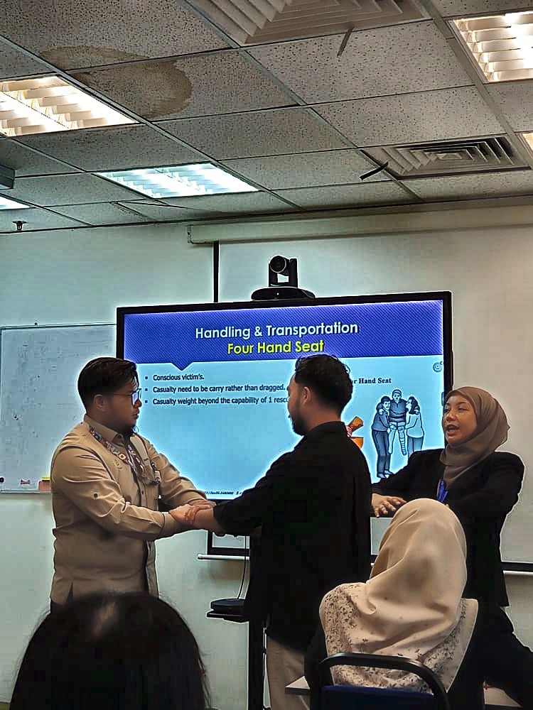 Participants practising the four-hand seat casualty carry during HRD Corp first aid training